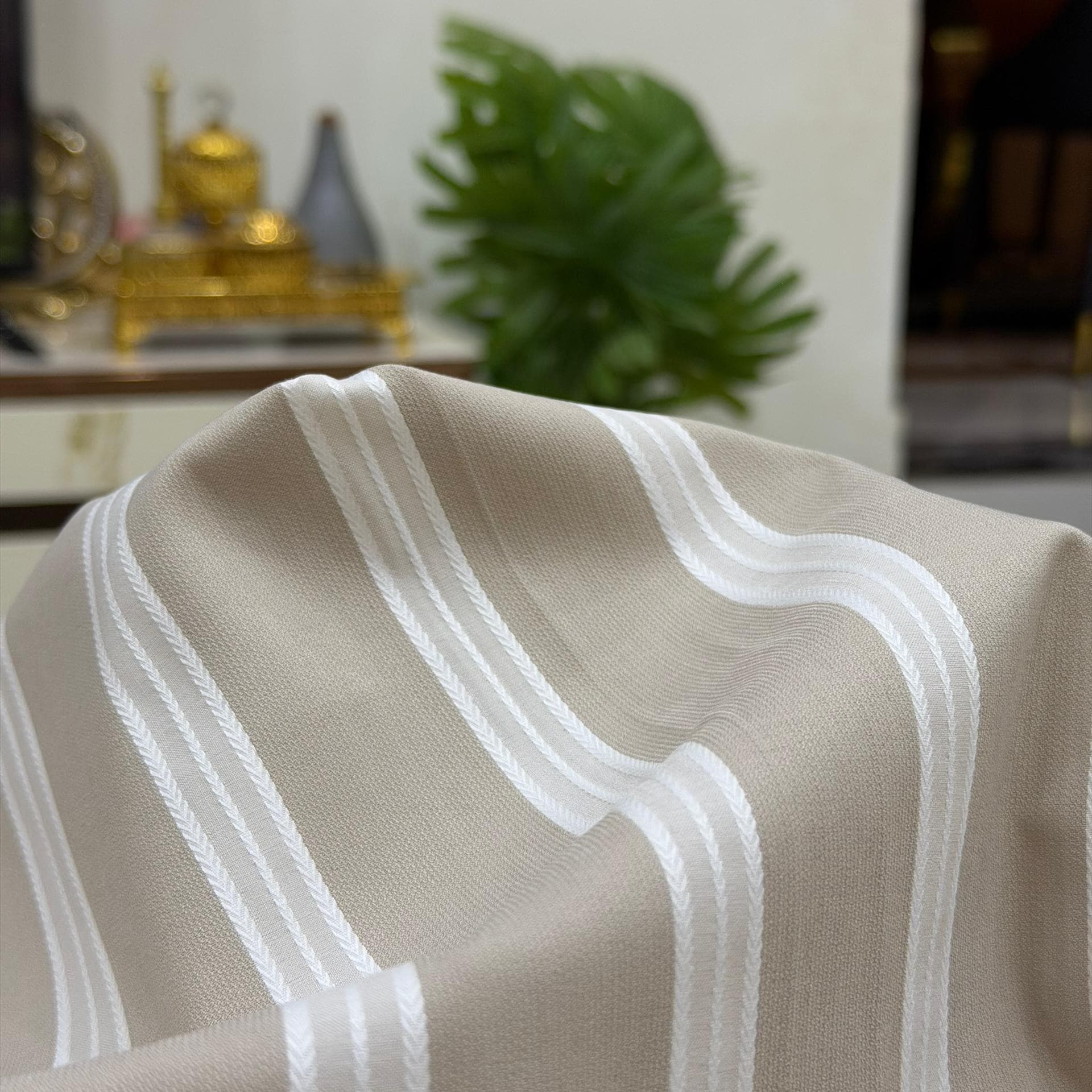 Taupe fabric with a wide white woven stripe draped over a table